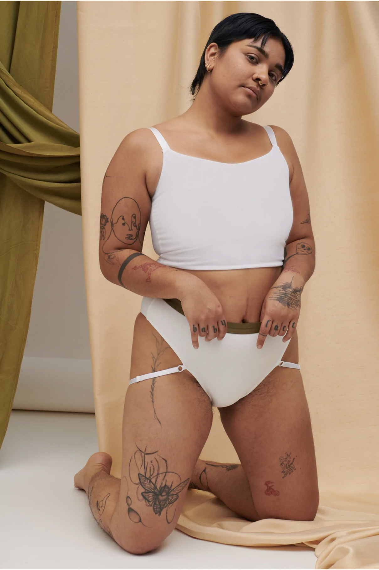 gender non descript tan person wearing a cropped white tank and white underwear positioned on their knees